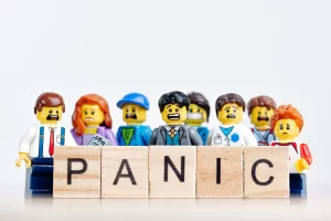 Image depicting panic and anxiety, with Lego figures expressing fear and the word "PANIC" spelled out in front of them.
