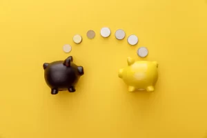 A black piggy bank and a yellow piggy bank with a curved line of coins moving between them on a yellow background.